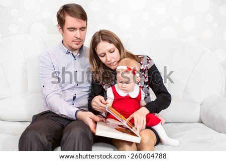 Father and mother opening book for baby reading