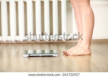 Human legs standing near floor weight scale for weighing