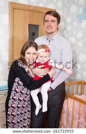 Young family three people standing together in bedroom