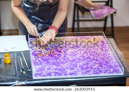 Painter hands splashing inks on water surface for marbling