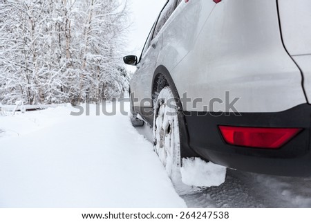Rear view of snow tires of car driving over snowdrift, winter season