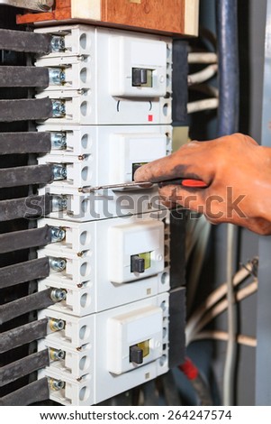 Electrician hand in rubber glove screwing with screwdriver in high voltage box
