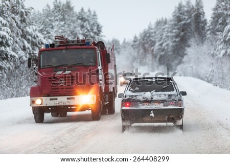 SEGEZHA, KARELIA, RUSSIA - CIRCA DEC, 2014: fire fighting truck and cars are on the Kola highway in winter season. The Kola is a federal road from St. Petersburg to Murmansk