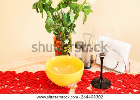 Still life with wine glass, plate and flowers on the kitchen table