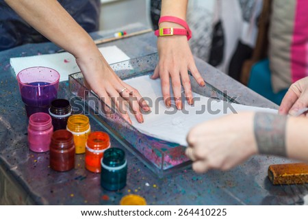 Women putting silk on water surface for color inks printing into silk, ebru art