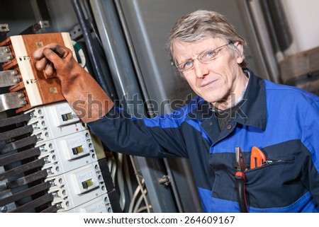 Senior electrical service repairman turning off main switcher in panel