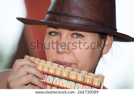 Young country woman in cowboy hat playing the panpipe