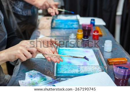 Hands of people which splashing paint over water surface, marbling