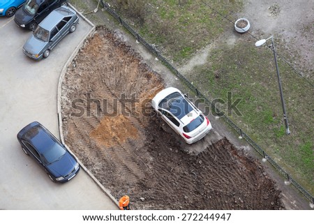 ST. PETERSBURG, RUSSIA - CIRCA APR, 2015: Wrong parking vehicle is on lawn while construction machinery works for extension of parking area of apartment building. Creation of living environment