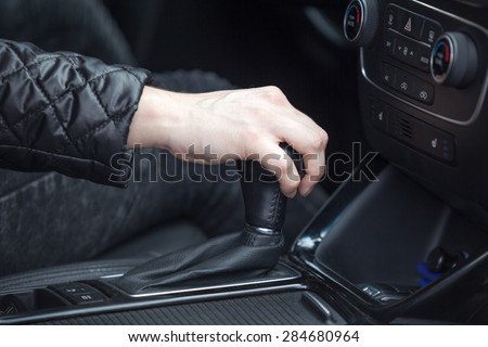 Caucasian female hand changing levels of automatic car gearbox, driver seat close up view