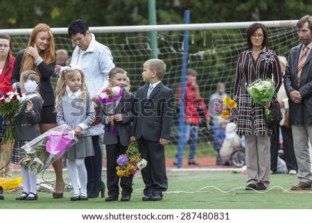 ST. PETERSBURG, RUSSIA - SEP, 1, 2014: First-grade students and teacher are in schoolyard. Children go back to school at first time in September