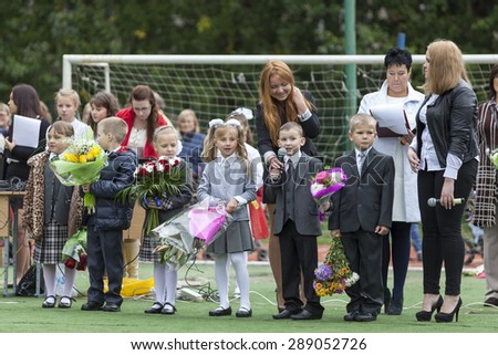 ST. PETERSBURG, RUSSIA - SEP, 1, 2014: First-grade pupils and teacher are in schoolyard. Children go back to school at first time in September