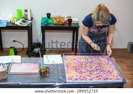 Woman painter making pattern on water surface with inks and stick