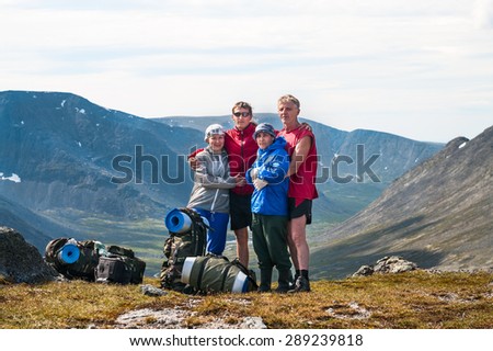 Four people family standing on the top of mountain pass together, hiking together