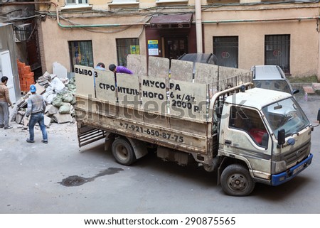 ST. PETERSBURG, RUSSIA - CIRCA JUN, 2015: Manual workers load construction debris in small truck body. Recycling of construction waste during a new interior finishing