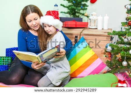 Mother reading the book daughter at the night before the Christmas