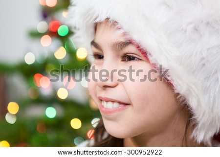 Preteen girl facial portrait on Christmas tree light background, copy space