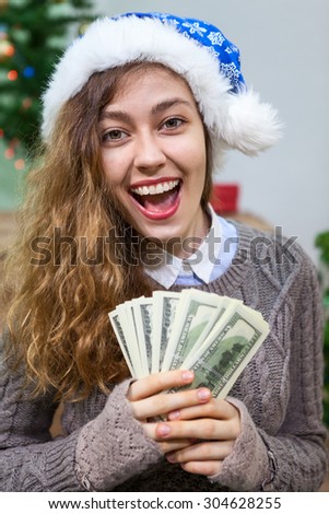 Happy and laughing young woman with cash money in hands as present at Christmas eve