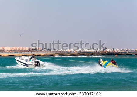 HURGHADA, EGYPT - CIRCA NOV, 2015: People ride on the inflatable banana in the Red Sea bay with motor boat. Entertainment is on the Hurghada resort