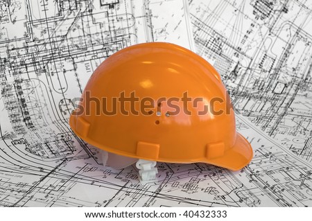 Orange constructional helmet and project drawings. Business objects on the construction dimensioned drawing