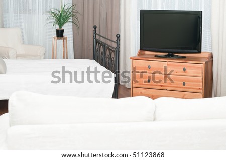 The big TV set in a room before a white sofa. A bedroom with a bed