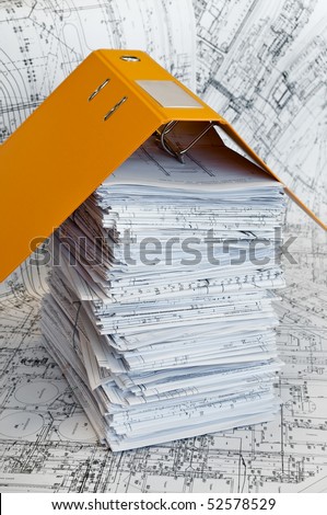 Big heap of design and project drawings under yellow folder on the table surface. White whatman are background.