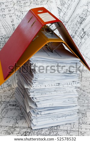 Big heap of design and project drawings under yellow and red folders on the table surface. White whatman are background.