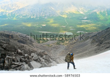 Man in mountain standing on peak of mountains and looking to far away