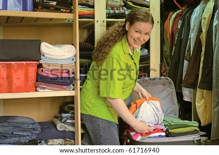 Young woman in the wardrobe packs things into a suitcase