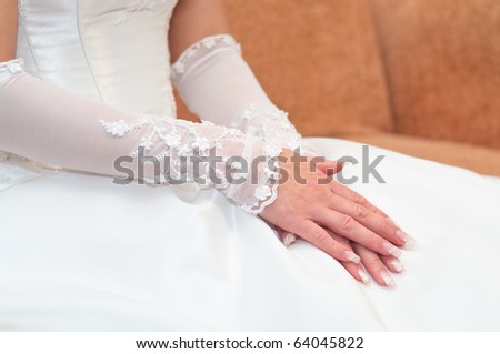 Women\'s hands on a white wedding dress. Bride seating, unrecognizable