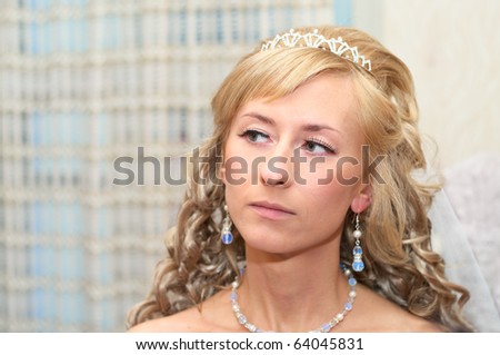 Portrait of a young beautiful girl with curly blonde curly hair. Jewelry around her neck and in ears. Close-up