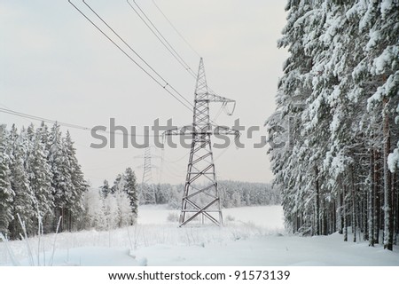High-voltage electric lines laid on the snowy evergreen northern woods in Russia