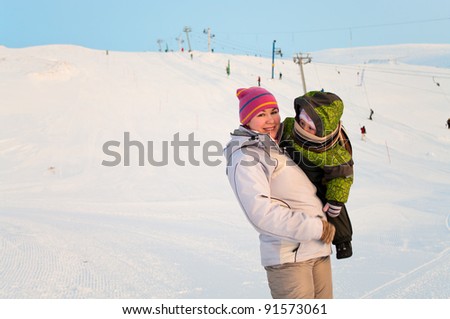 Mother and her little child standing on winter ski mountain