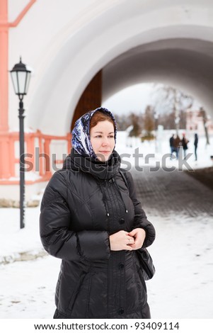 Russian woman in winter clothes against Orthodox monastery building. Pilgrimage