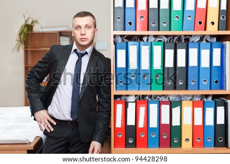 Handsome male business executive standing behind a bookstand