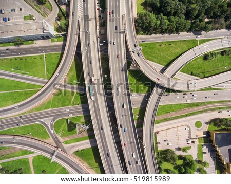 Aerial view at junctions of city highway. Vehicles drive on roads. Russia