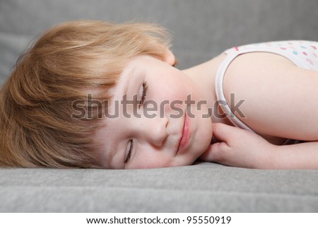Small Caucasian girl sleeping on couch. Close up portrait