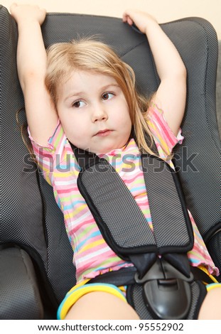 Small girl sitting in a car safety seat with seatbelt