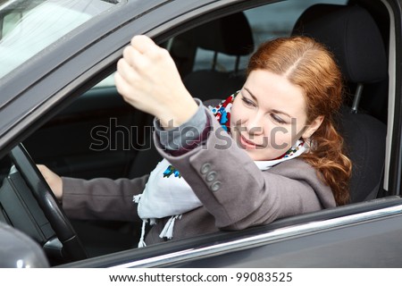 Pretty young Caucasian woman shaking hers fist sitting in car