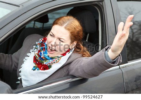 Pretty young Caucasian woman shaking hers fist sitting in car