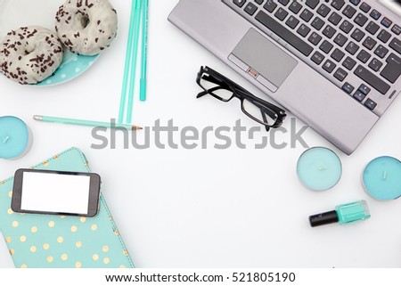 Flat lay, top view office table desk frame. Workspace with laptop, mint candle, mint diary, nail polish and mobile device and  donuts on white background.