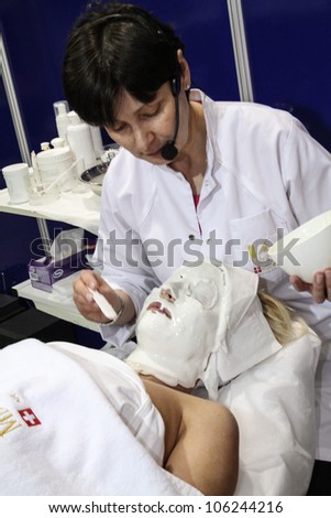 MOSCOW-APRIL 19: Cosmetician doing cosmetic mask at the international exhibition of professional cosmetics and beauty salon equipment INTERCHARM on April 19, 2012 in Moscow
