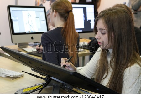 MOSCOW- OCTOBER 7:  Unidentified young girl artist draws a digital pen at the international exhibition of  the entertainment industry, Igromir on October 7, 2012 in Moscow