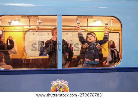 MOSCOW - MAY 5, 2015: Unidentified child opens a window in an old subway car at the exhibition of retro-cars dedicated to the 80th anniversary of the Moscow Metro. Public-event