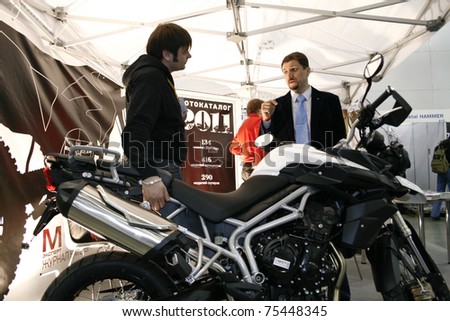 MOSCOW - APRIL 1: Man consults on the motorcycle Triumph Tiger at the Moscow specialized Exhibition  of motor cycling industry in Russia on April 1, 2011 in Moscow, Russia