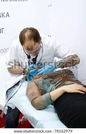 MOSCOW - APRIL 15: Unidentified cosmetician does permanent makeup tattoo at the international exhibition of professional cosmetics and beauty salon equipment \