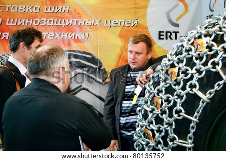 MOSCOW - APRIL 13: Men discuss tire with chain at the international exhibition of  the Mining and Processing of Metals and Minerals, MiningWorld on April 13, 2011 in Moscow