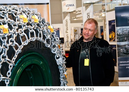 MOSCOW - APRIL 13: Man looks at the tire with chain at the international exhibition of  the Mining and Processing of Metals and Minerals, MiningWorld on April 13, 2011 in Moscow