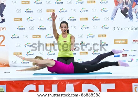 MOSCOW - OCTOBER 5: Woman doing stretching by leadership of coach at the international exhibition of the fitness and wellness industry, MIOFF on October 5, 2011 in Moscow