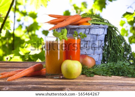 Apple and carrot juice and fresh fruits with leaves on wood